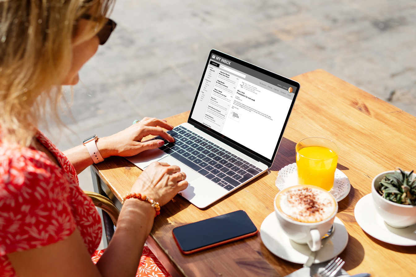 Woman reading emails on laptop at café.